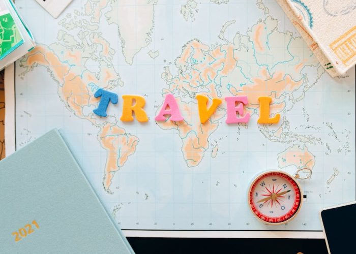 pexels-photo-7235893-7235893-1 Flat lay of a map with colorful letters "TRAVEL" and a compass for planning adventures.